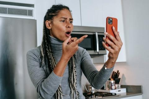 Girl holding up and looking at smartphone with appalled look on her face