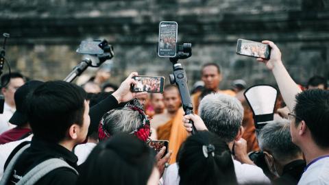A large crowd gathers around while holding up their phones to shoot video