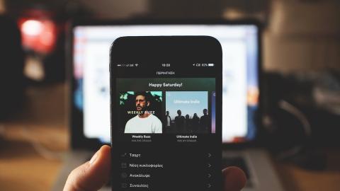 A hand holding a smartphone that's displaying a Spotify screen