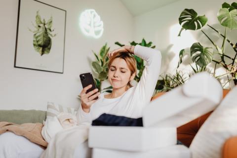 Female at home looking at her phone with arm raised seemingly in frustration