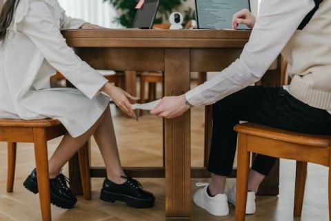 Two hands passing a note to each other under a table